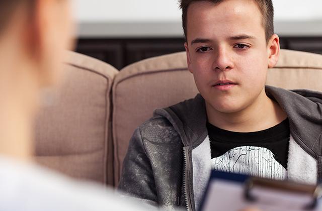 Young teenager boy at counseling - talking to the therapy professional, close up