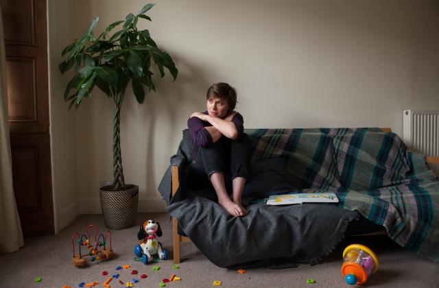 Woman sitting alone in a living room by a sofa 