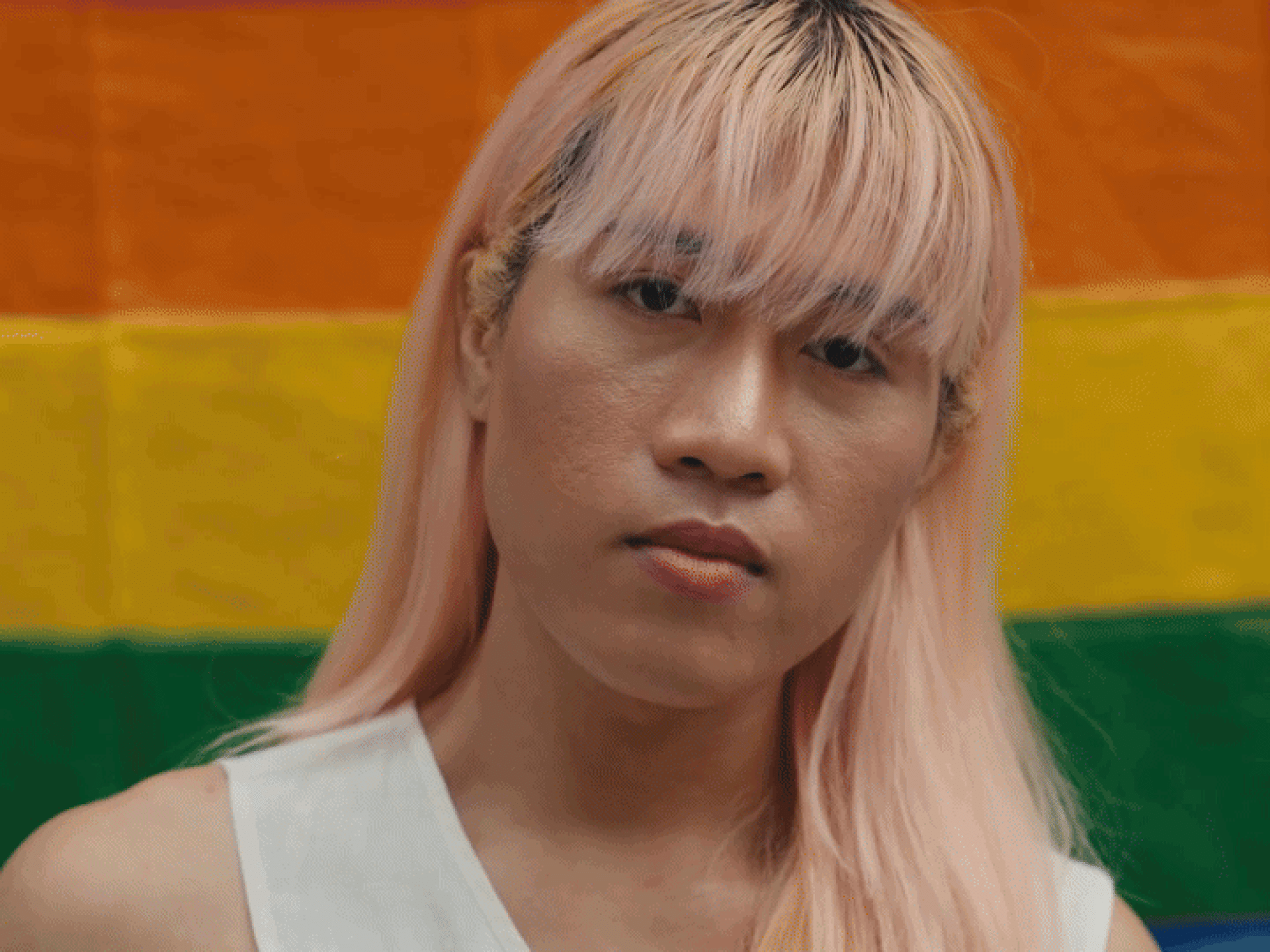 The video starts with a close up of a trans woman standing in front of a rainbow flag, looking in camera with a strong expression. The following video portrays a young man with down syndrome with his arms crossed. He is portrayed at work, in a flower farm. This is followed by a video of a young woman of African descent looking in camera while walking in a big city. The video is closed by footage of an elderly man in a park, wearing a hat, looking in camera.